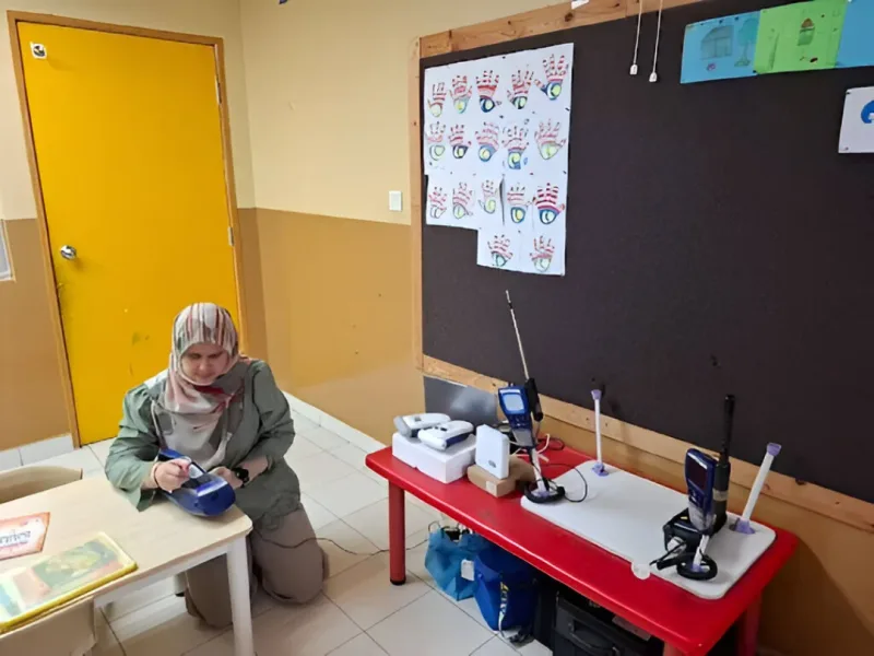 An AirGradient ONE monitor is being prepared for indoor air quality measurements in a preschool classroom.